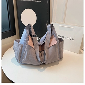Detail of grey-blue nylon tote bag with pink contrast trim and adjustable metal buckle
