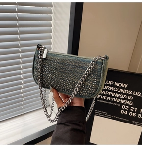 Detail of light blue denim handbag featuring metallic studs and chunky silver chain strap