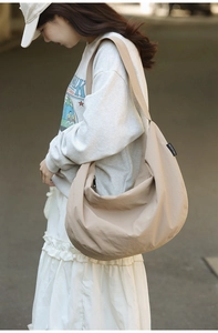 Detail of khaki nylon crescent bag with wide shoulder strap and brand woven label
