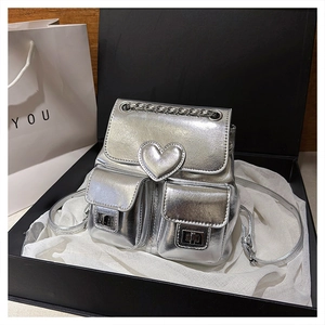 Detailed close-up of a metallic silver mini backpack with heart stitching and metal locks
