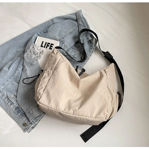 Detail view of beige canvas tote bag with adjustable black drawstrings and nylon strap