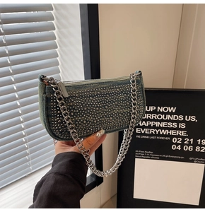Detail of blue denim baguette bag featuring silver studs and metallic chain strap