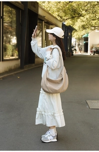 Detail of khaki crescent shoulder bag with wide strap and soft texture in street style