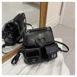 Close-up of black leather backpack with heart patch, metal locks and chain straps