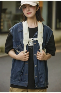 Dettaglio del cinturino funzionale crema indossato sopra gilet di jeans e maglia nera