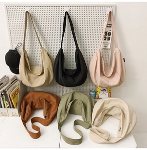 Detailed close-up of crescent nylon tote bags in six colors arranged in a lifestyle setting