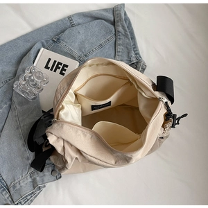 Detail of off-white nylon crossbody bag interior pockets and textured fabric surface