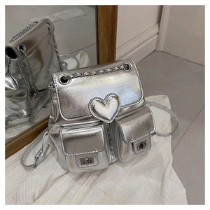 Detail view of silver mini backpack with heart decoration, chain straps and metal twist locks