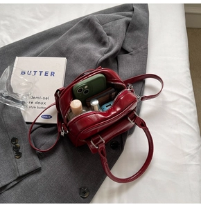 Interior detail of red leather handbag showing compartments with phone and cosmetics