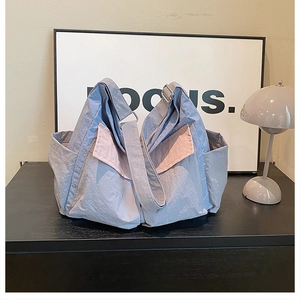 Detail view of light blue and pink canvas messenger bag with side pockets and crinkled texture