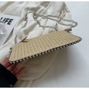 Detail of hand-woven rectangular straw bag with silver metal beads and chain strap