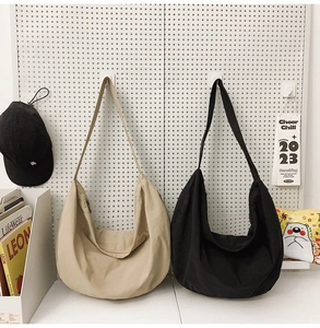 Detail of minimalist nylon hobo bags in beige and black with wide shoulder straps