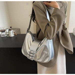 Detail of silver half-moon shoulder bag with triple decorative metal buckles for women
