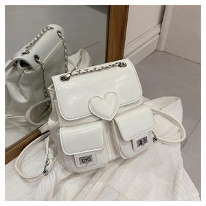 Close-up of white PU leather mini backpack with heart decor and silver metal locks