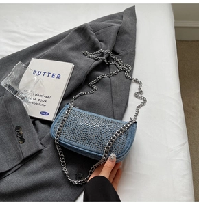 Detail of blue denim mini bag featuring silver rhinestones and metal chain strap