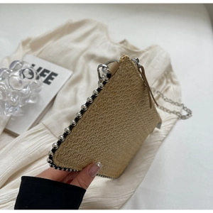 Detail of straw woven clutch bag with silver bead trim and metallic chain strap
