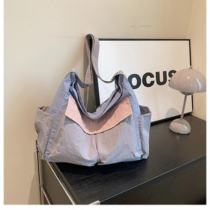 Detail of grey-blue and pink canvas hobo bag with side pocket on a minimalist wooden cabinet