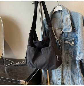 Detail of black nylon tote bag featuring side pockets and a woven brand label