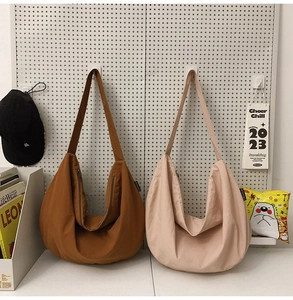 Detail view of large nylon crescent shoulder bags in dark brown and light pink colors
