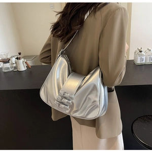 Detail view of silver metallic Y2K shoulder bag with triple buckle straps and wrinkled texture