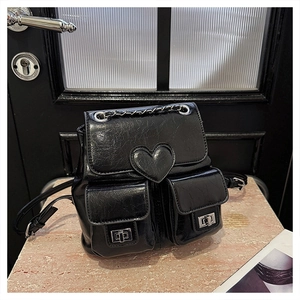Detail shot of black patent leather backpack with heart motif and silver metal buckles