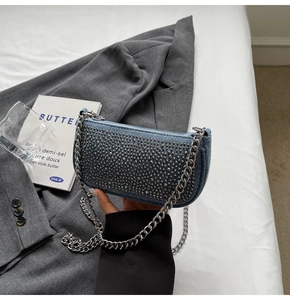 Detail of blue denim shoulder bag with silver studs and chunky chain strap