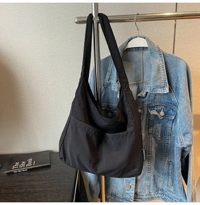 Detail shot of large black canvas tote bag with front pockets on a metal rack