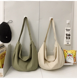 Detail view of olive green and off-white nylon crescent bags hanging with minimalist props