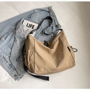 Detail of khaki crescent crossbody bag with drawstring and adjustable black shoulder strap