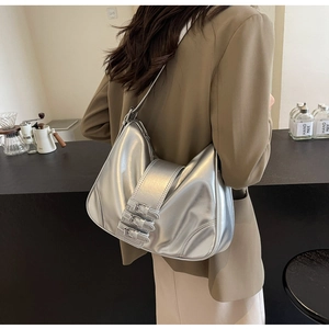 Close-up of metallic silver shoulder bag with triple buckle design on a model