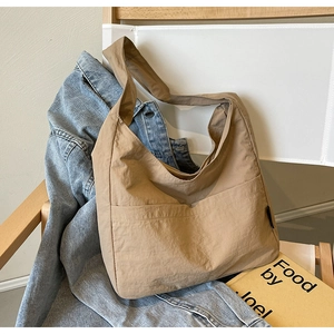 Detail view of khaki large capacity tote bag with front pockets on a wooden chair
