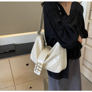 Detail of creamy glossy leather shoulder bag with three silver buckles and pleated texture