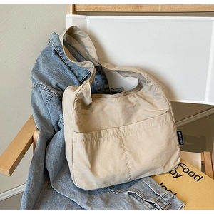 Detail of light beige tote bag with two front pockets on a minimalist chair