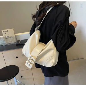 Detail of cream glossy patent leather underarm bag with triple buckle strap design