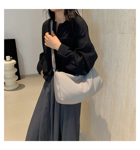 Detail van de grijze nylon crossbodytas op model met focus op de grote inhoud en de riem