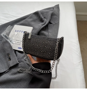 Detail of black fabric handbag with silver rivets and heavy metal chain strap