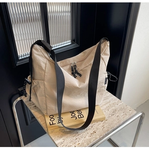 Detail view of large beige canvas messenger bag with adjustable strap and dual zippers