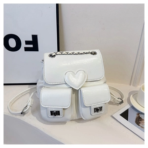 Close-up of white leather backpack featuring decorative heart and stylish chain handle