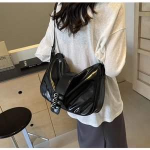 Detail showing side silver buckles and glossy leather texture on black hobo shoulder bag