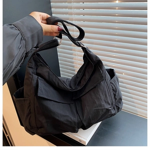 Detail of black high-density canvas messenger bag with wide strap and silver buckle