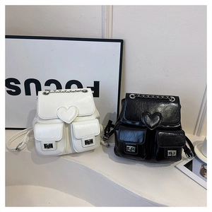 Detail view of heart-quilted leather backpacks in black and white with chain handles
