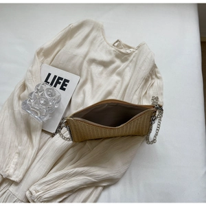 Detail of woven straw envelope bag texture with silver metal chain and zipper
