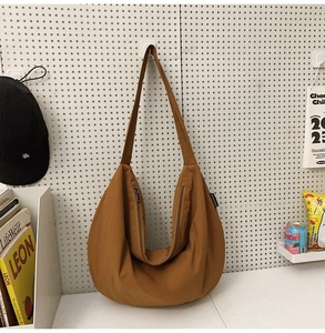 Detail view of a brown nylon crescent shoulder bag featuring a smooth double zipper closure