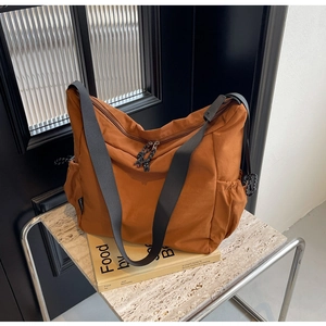 Detail of caramel nylon tote bag with wide black strap and side storage pocket