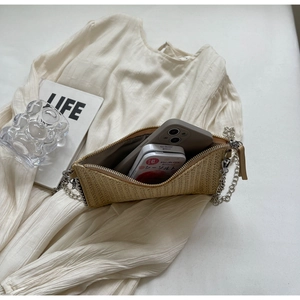 Detail view of woven straw crossbody bag showing storage capacity for a smartphone