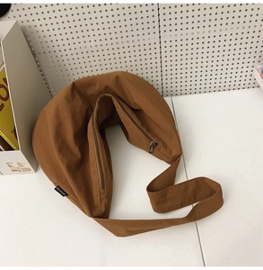 Detail view of the brown nylon crescent shoulder bag featuring a side brand label