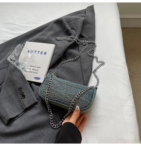 Detail of washed denim shoulder bag with silver studs and elegant metal chain strap