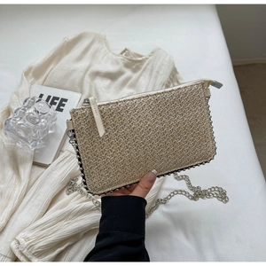 Detail of woven straw clutch bag with silver bead edges and metallic chain strap