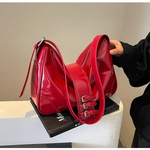 Detail view of red glossy patent leather shoulder bag with vintage silver buckle straps