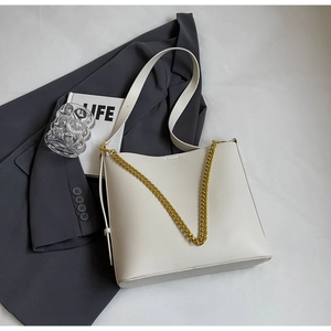 Top view of cream large tote bag with gold chain strap on grey blazer with a glass